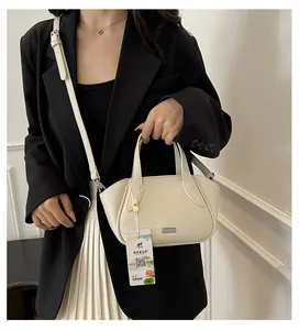 Detail der cremeweißen Lederhandtasche mit Litschi-Muster, Silberlogo und Schultergurt