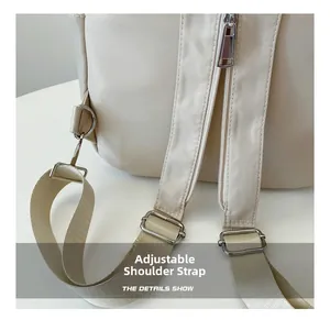 Detail view of adjustable nylon shoulder straps with silver metal hardware on a cream backpack