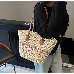 Detail of hand-woven straw tote with brown leather straps and woven pattern accents