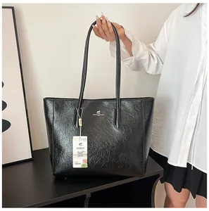 Detail of black faux leather tote bag with silver kangaroo logo and refined texture