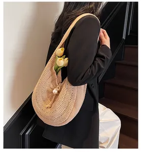 Detail of beige woven tote bag featuring a large pearl accent and textured straw material