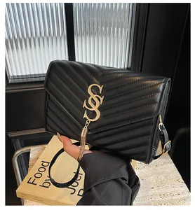 Detail einer schwarzen gesteppten Ledertasche mit goldenem Logo und Quasten-Anhänger