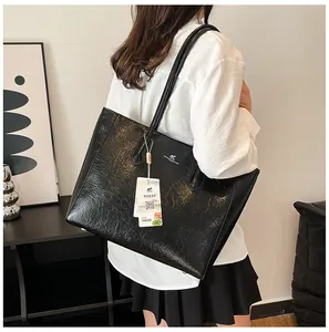 Detail of large black leather tote bag showing glossy texture and kangaroo brand logo