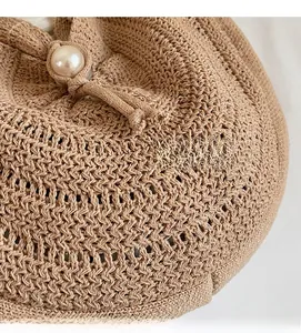 Detail of hollow woven straw bag featuring pearl drawstring closure and fine texture
