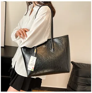 Detail of black glossy crackled leather tote bag with elegant shoulder strap and metal logo