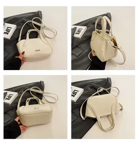 Detailansicht der cremefarbenen Ledertasche mit Lychee-Narbung und Metallelementen