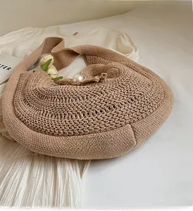 Detail of hand-woven beige tote bag featuring a large pearl clasp and crochet texture