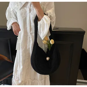 Detail of hand-woven black shoulder bag with pearl button and floral arrangement