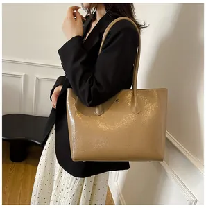 Detail of khaki leather tote with kangaroo logo on model in chic office outfit