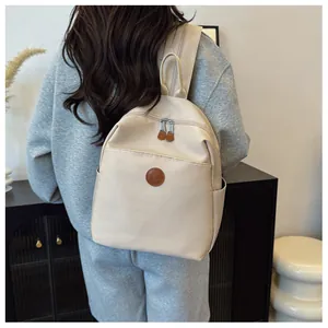 Lifestyle view of a cream nylon backpack showing large capacity and adjustable straps