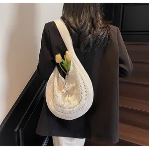 Detail of white crochet shoulder bag featuring pearl decor and drawstring closure
