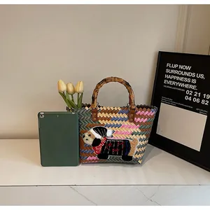 Detail of colorful woven tote bag featuring bamboo handle and embroidered cartoon dog