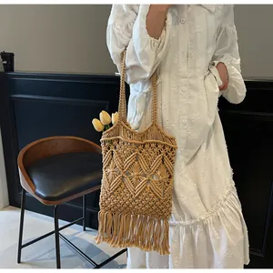 Détail d'un sac cabas bohème en paille avec de longues franges et motifs géométriques