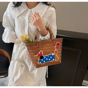 Detail view of woven tote bag with dachshund embroidery and bamboo handle