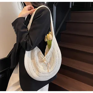 Detail of cream crochet tote bag with pearl accent on woven openwork shoulder strap