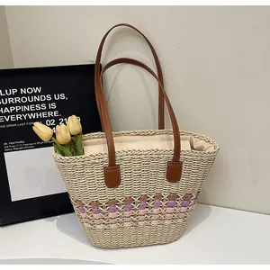 Detailed view of woven straw tote bag featuring colorful wave patterns and leather straps