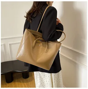 Close-up of khaki wrinkled leather tote bag with kangaroo logo on model's shoulder