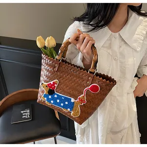 Detail of woven brown tote bag with carbonized bamboo handle and dachshund embroidery