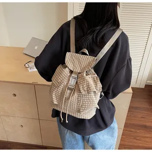 Detail of plaid canvas backpack featuring drawstring closure and adjustable straps