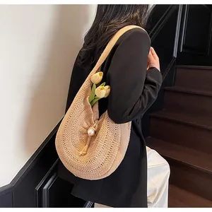 Detail of hand-woven straw shoulder bag featuring a pearl clasp and textured crescent shape