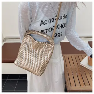 Détail d'un sac à main tissé champagne avec poignée ronde et bandoulière amovible