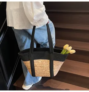 Detail of straw woven tote with black fabric handles and a yellow tulip inside