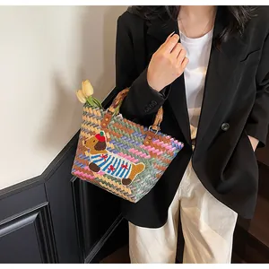 Detail of colorful woven tote bag featuring a cute cartoon dog and bamboo handle