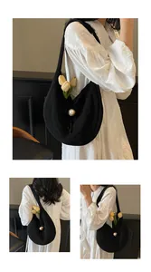 Detail of black crochet hobo bag with pearl buckle on white embroidered dress