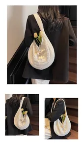 Detailed close-up of cream knit shoulder bag featuring woven texture and pearl drawstring