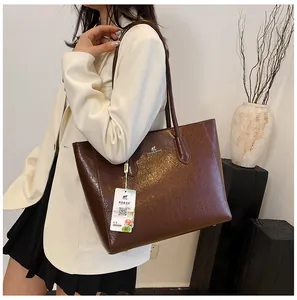 Detail of a dark brown vintage tote bag with wrinkled leather texture and silver logo