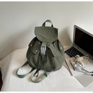 Detail of dark green gingham canvas backpack with drawstring closure and front buckle pockets