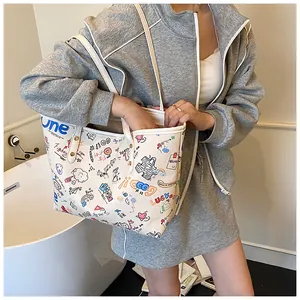 Detail of white canvas tote bag featuring colorful graffiti prints and leather straps