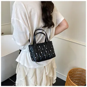 Detail of black quilted shoulder bag with silver beads and elegant chain strap for women