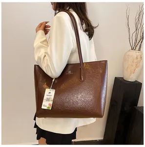 Detail of dark brown tote bag with glossy wrinkled texture and silver logo on shoulder
