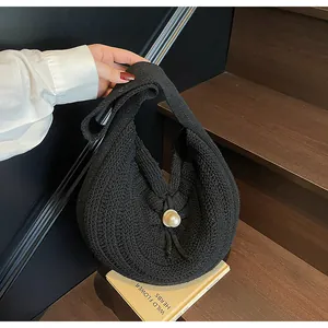 Detail of black knit hobo bag with oversized pearl closure and textured crochet pattern