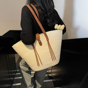 Large beige woven straw tote bag with brown leather straps for beach vacation or commuting