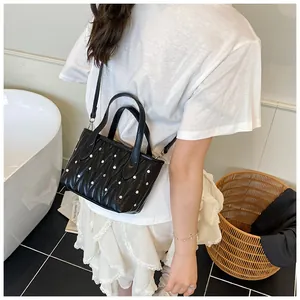 Close-up of black quilted mini bag with silver studs and ruffled leather texture