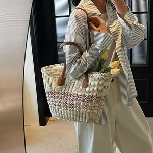 Handwoven straw tote bag with floral patterns and brown leather straps for summer beach use