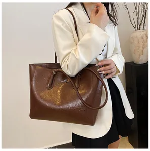 Detailed view of dark brown tote bag with wrinkled leather texture and zipper detail