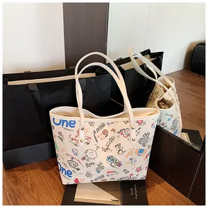 Detail of cream tote bag featuring colorful graffiti prints and long shoulder straps