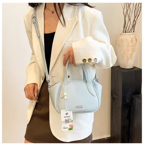 Detailansicht der hellblauen Lederhandtasche mit Lychee-Muster zu weißem Blazer