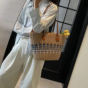 Handwoven straw tote bag with blue-purple patterns and brown leather straps for beach
