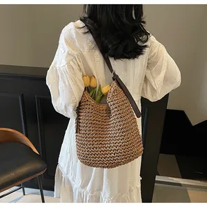 Detail showing the woven straw texture and leather strap of this large beach shoulder bag