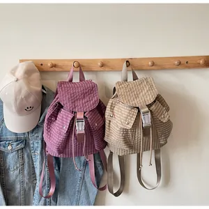 Detail of plaid canvas backpacks with buckle closure and drawstring in purple and beige