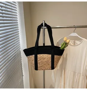 Detail of a contrast straw tote bag with black webbing handles in a sunny home setting