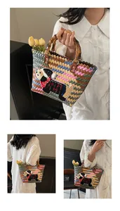 Detail of woven tote bag with dachshund patch and natural bamboo top handles