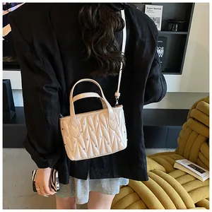 Detailed close-up of beige quilted crossbody bag with rhinestone accents and chain strap