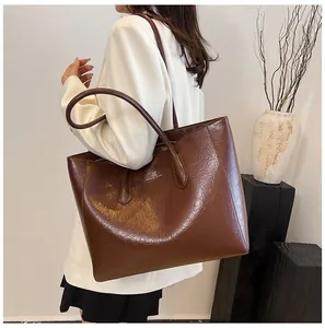 Deep brown oil-wax leather tote bag showing spacious design and refined metal logo