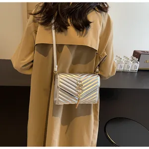 Silberne gesteppte Umhängetasche mit goldenem Logo und Quaste auf einem Frauenmodell