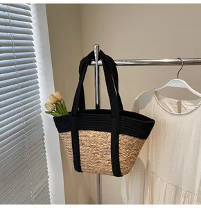 Detail of summer straw tote bag featuring black canvas trim and woven fiber texture